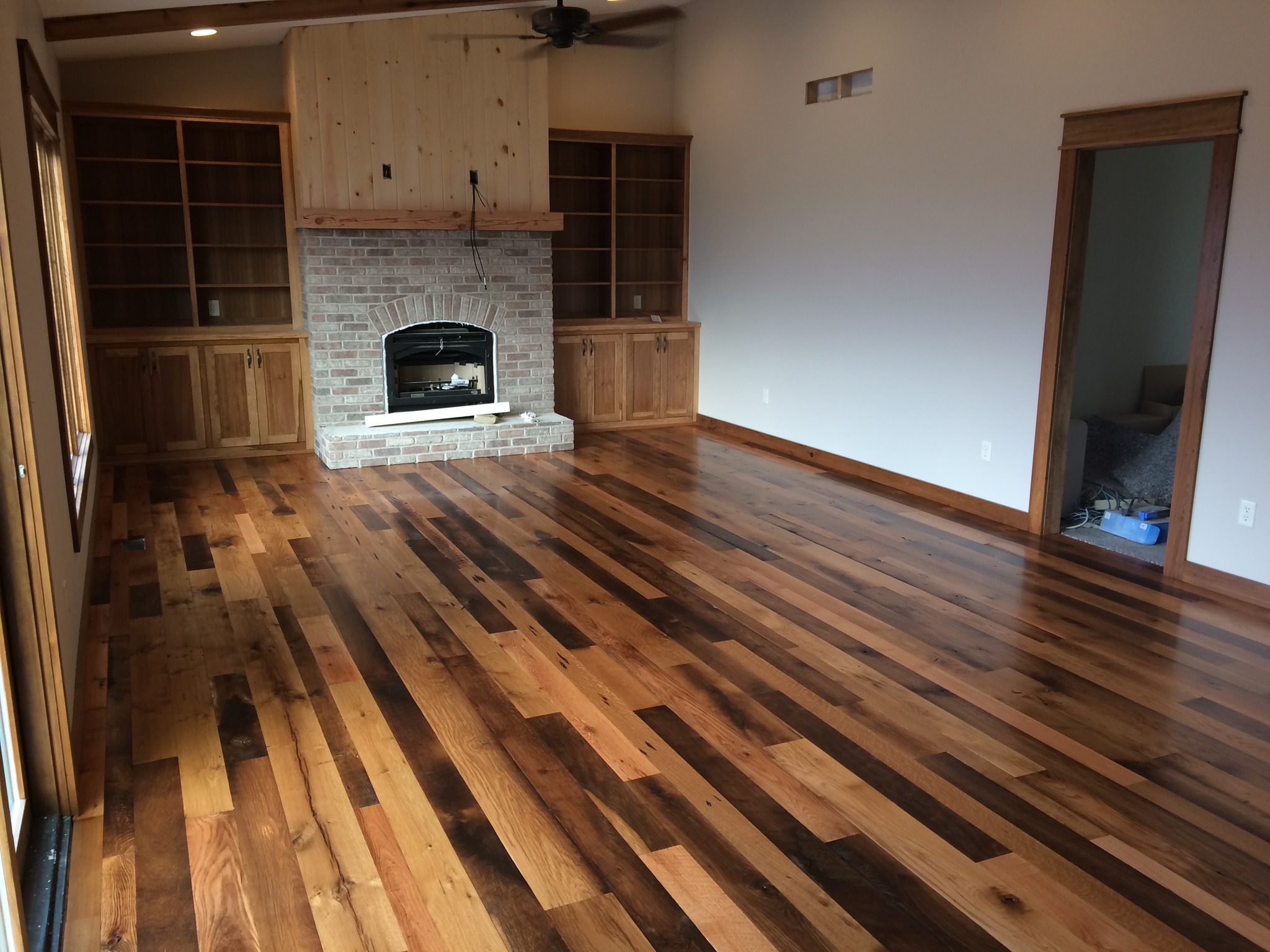 Reclaimed wood floor that was sanded and finished on site, showcasing a stone fireplace.