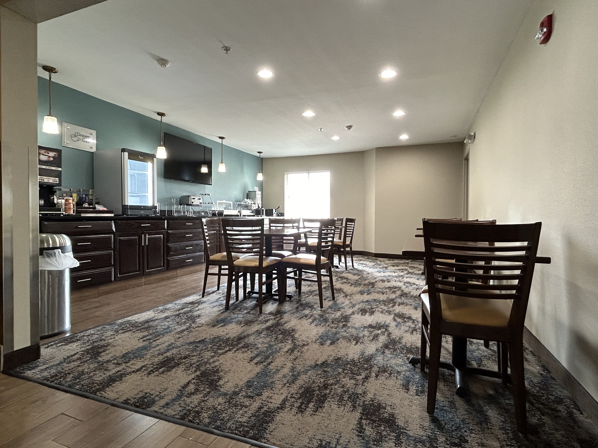 Hotel breakfast area with tables and chairs, with newly installed carpeting.